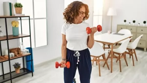 older female doing bicep curls at home